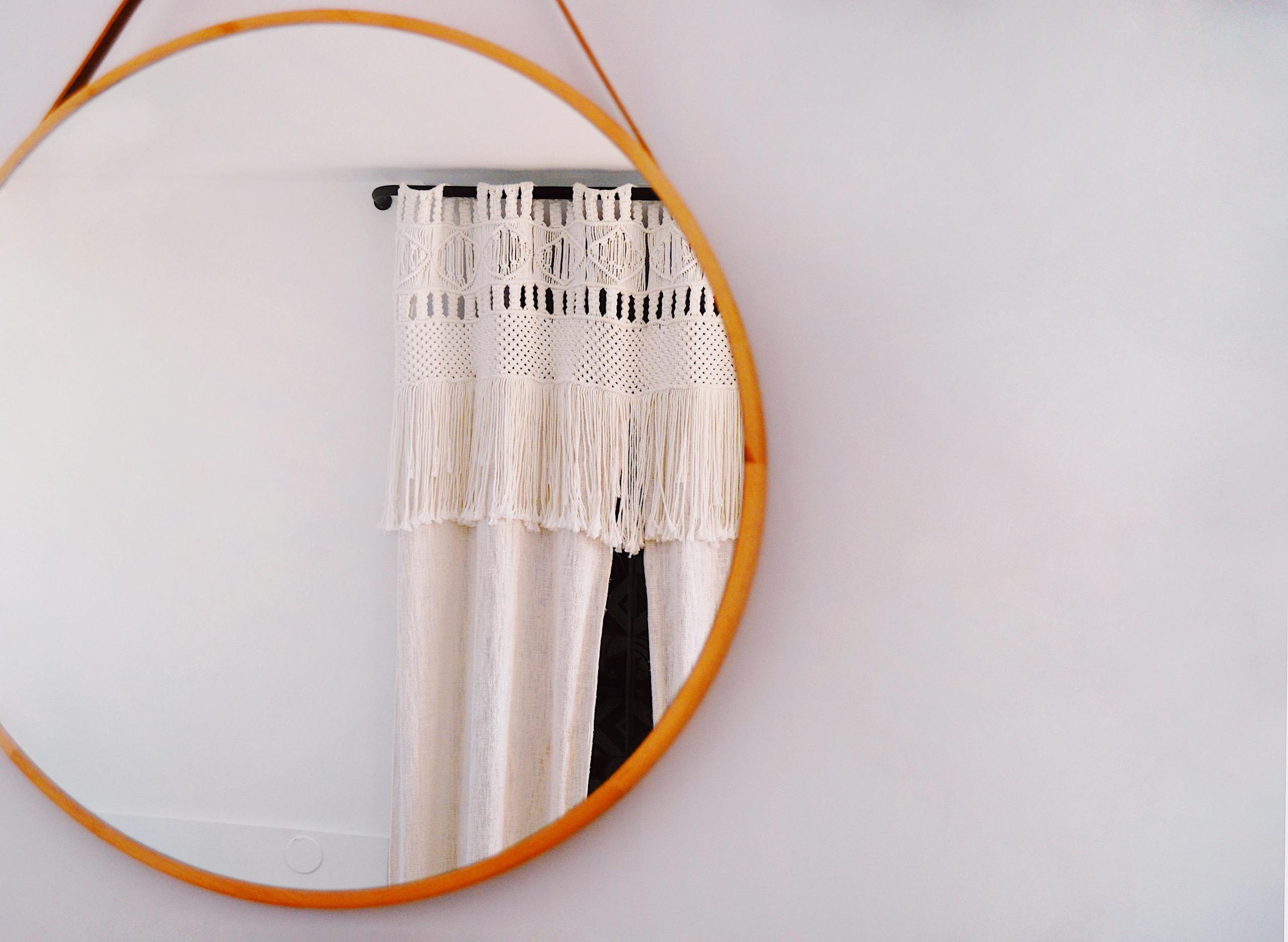 Round Brown Framed Mirror With Reflection of Curtain